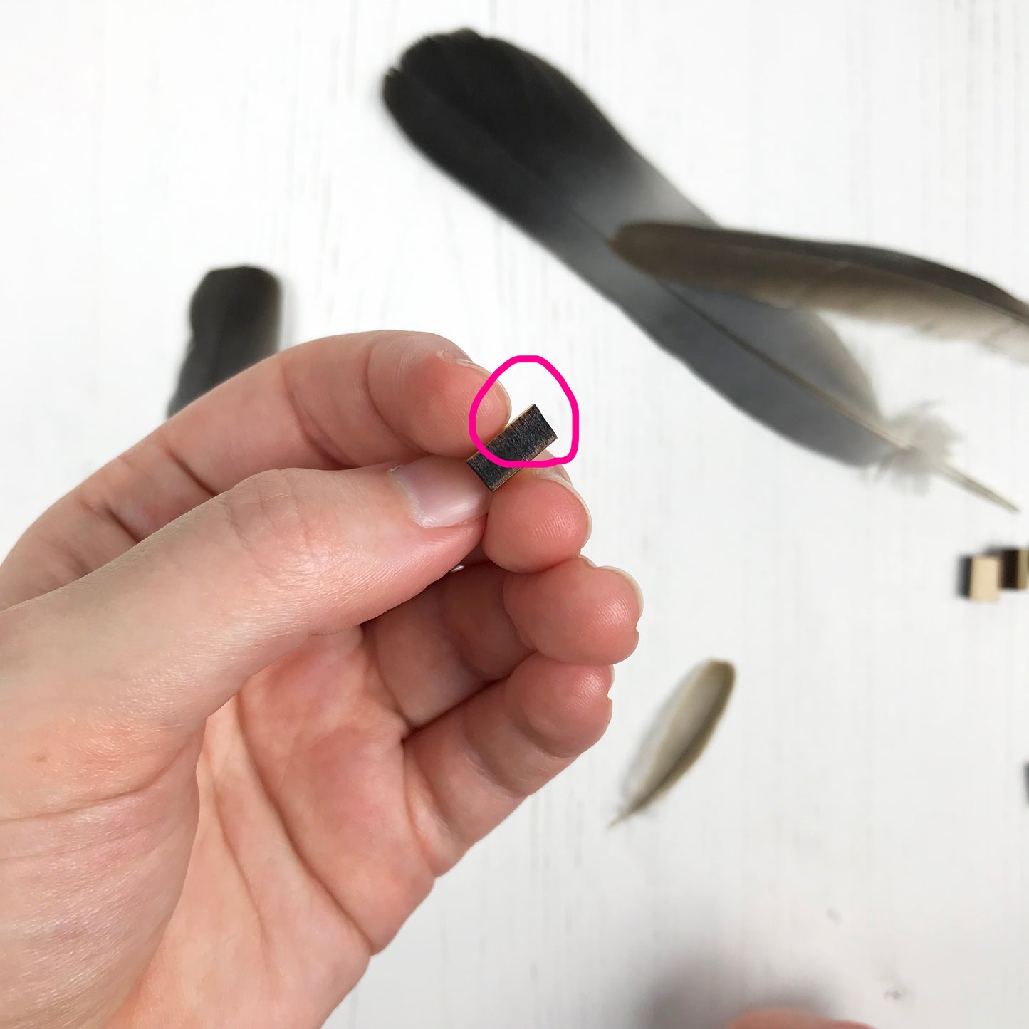 A laser cut wooden stud earring second by loadofolbobbins showing a silhouette scene inspired by the novel Jane Eyre by Charlotte Brontë. The stud is side on and a pink circle is highlighting where the edge is going off at and angle, not straight at the edges.