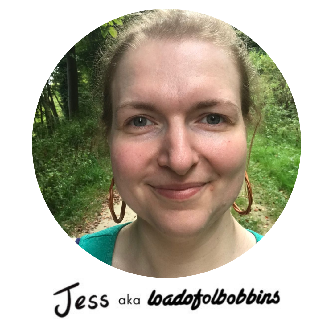 A photograph of Jess aka Loadofolbobbins a smiling and friendly looking white woman with hair up and standing in a forest path.