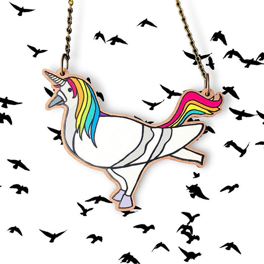 A laser cut wooden necklace showing an original digital illustration by Loadofolbobbins of a pigeon cosplaying as a unicorn. The main and tail of the unicorn are in vibrant rainbow colours and the overall colouring of the body is a light grey white where you can see the original pigeon markings underneath. The pigeons feet have been changed into little hooves and it has a magnificent unicorn horn on its head. The style of the illustration is a simplified flat colour one with black outlines.