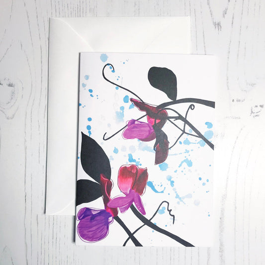 An A6 greetings card showing an illustration of sweet peas against an inky blue wash background. The purple sweet peas flowers are in colour with the plant leaves and stems silhouetted in black.