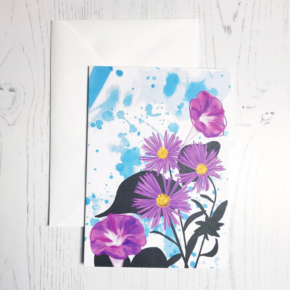 An A6 greetings card showing an illustration of purple morning glories and asters against an inky blue wash background. The flowers are in colour with the plant leaves silhouetted in black.