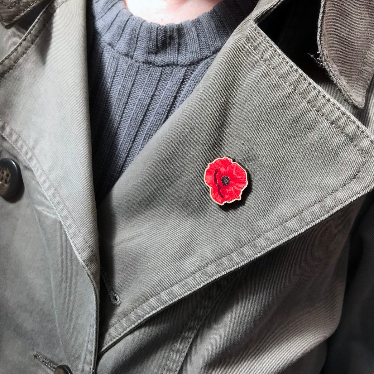 A 25mm mini wooden lapel pin of a red poppy flower worn on the lapel of a jacket The pin is made from an original illustration and is loose and expressive in style. 