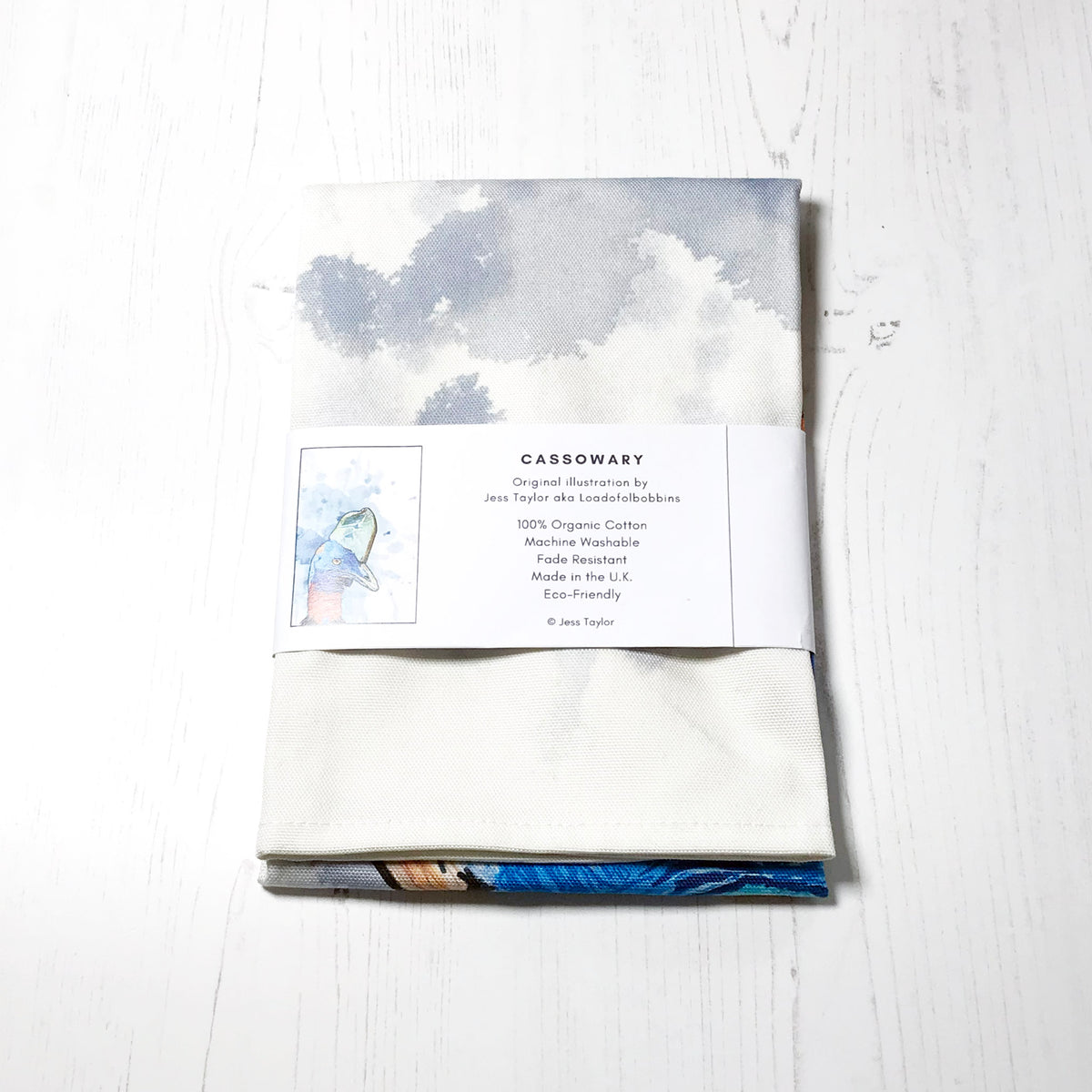 Text on a belly band around a folded tea towels they say Cassowary. Original llustration by Jess Taylor aka Loadofolbobbins. 100% organic cotton, machine washable, fade resistant,made in the UK, Eco friendly. Copyright Jess Taylor.