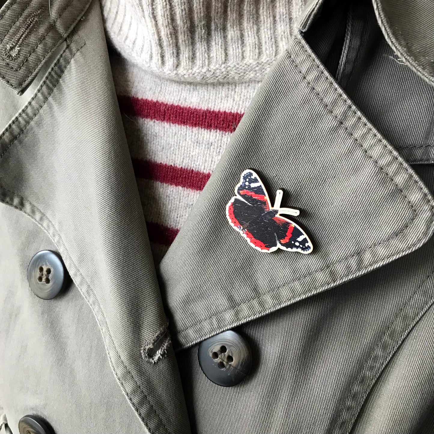 A laser cut wooden brooch showing an illustration by Loadofolbobbins of a Red Admiral Butterfly. The brooch is worn on the lapel of a jacket.